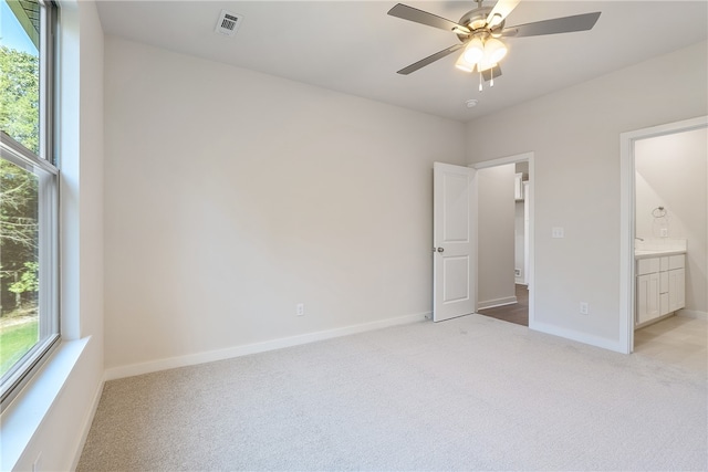 unfurnished bedroom with light carpet, ceiling fan, and ensuite bathroom