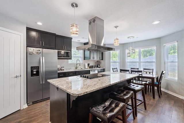 kitchen with decorative light fixtures, a center island, dark wood-type flooring, stainless steel appliances, and island range hood