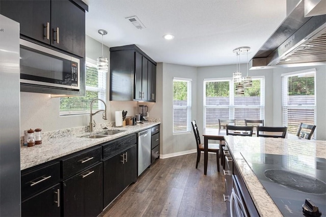 kitchen with appliances with stainless steel finishes, dark hardwood / wood-style flooring, light stone countertops, pendant lighting, and sink