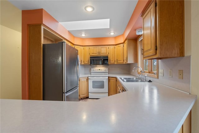 kitchen featuring white electric range, sink, a skylight, kitchen peninsula, and stainless steel refrigerator