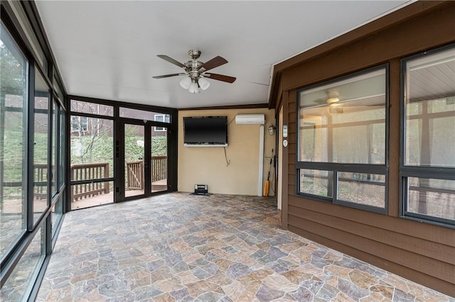 unfurnished sunroom with a wall mounted air conditioner, ceiling fan, and a healthy amount of sunlight