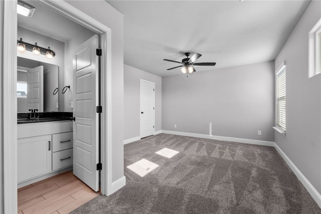 unfurnished bedroom with light colored carpet, ceiling fan, and sink