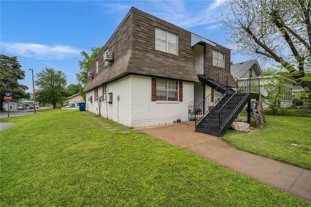 view of front of house with mansard roof, brick siding, roof with shingles, stairway, and a front lawn