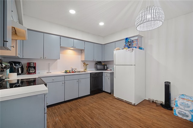 kitchen with wood finished floors, recessed lighting, a sink, black appliances, and light countertops