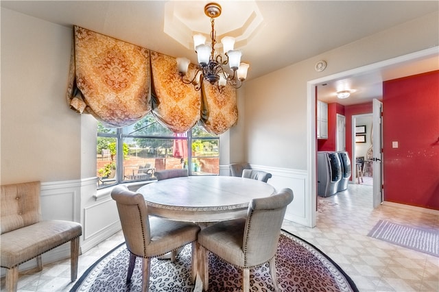 dining area featuring washer / clothes dryer, light tile patterned flooring, a chandelier, and a tray ceiling