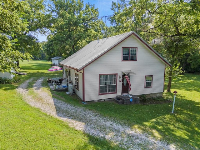 exterior space with a yard, metal roof, and driveway