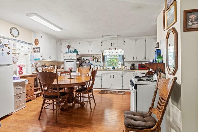 kitchen with white cabinetry, light wood-type flooring, and white appliances