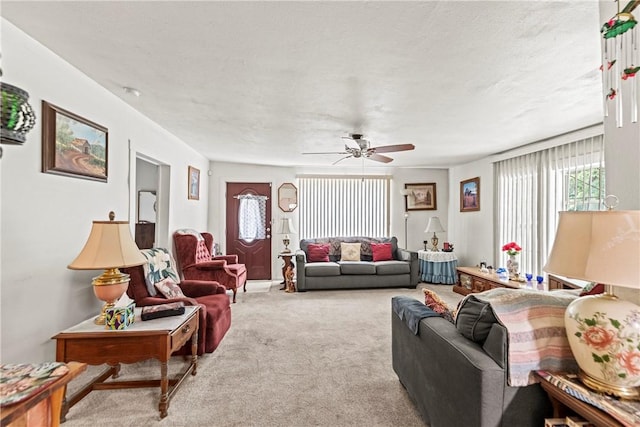 carpeted living area with ceiling fan and a textured ceiling