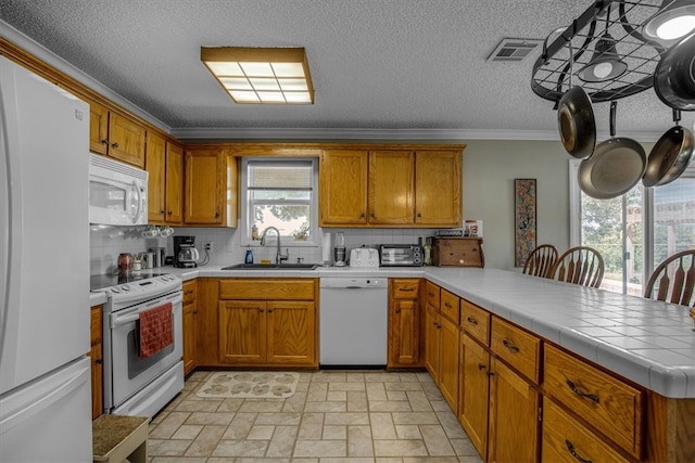 kitchen featuring light tile patterned flooring, white appliances, sink, tile counters, and a wealth of natural light