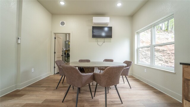 dining space featuring a wall mounted air conditioner and light hardwood / wood-style flooring