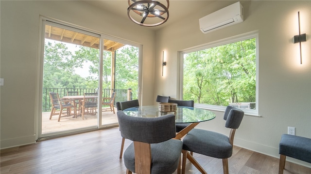 dining space featuring light hardwood / wood-style flooring, a wall unit AC, and a chandelier