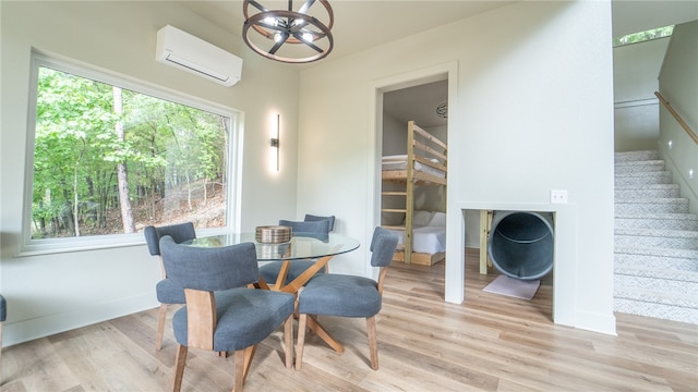 dining room featuring a notable chandelier, a wealth of natural light, a wall unit AC, and light wood-type flooring