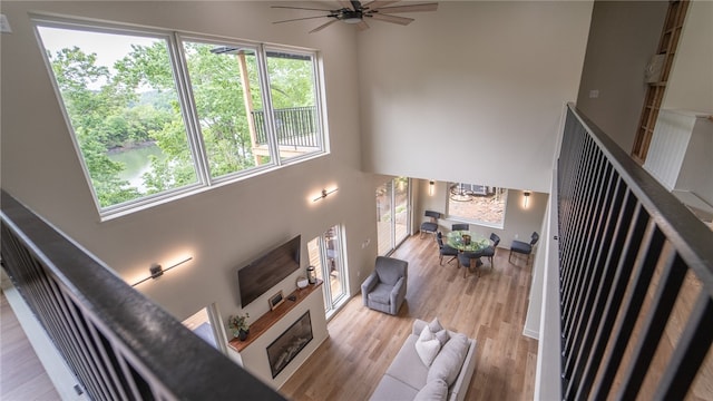 living room featuring ceiling fan, light hardwood / wood-style flooring, and a towering ceiling