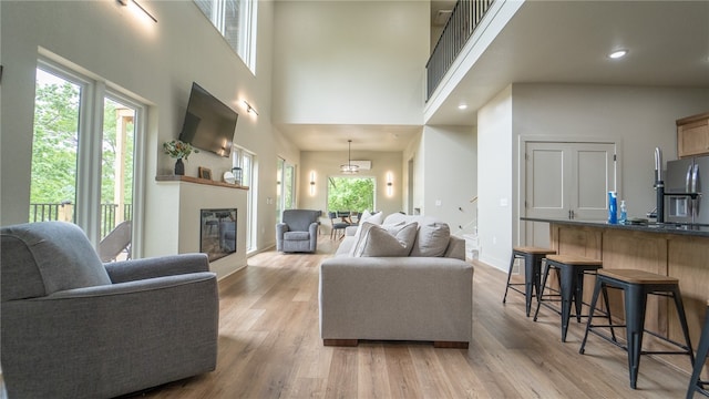 living room featuring light hardwood / wood-style floors, a chandelier, and a high ceiling