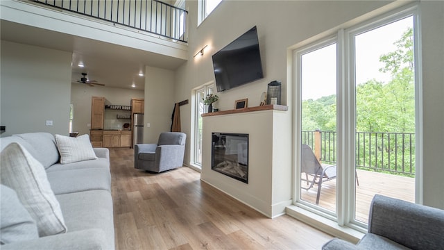 living room featuring light hardwood / wood-style flooring, a wealth of natural light, and ceiling fan