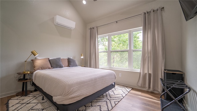 bedroom featuring vaulted ceiling, light hardwood / wood-style flooring, and a wall unit AC