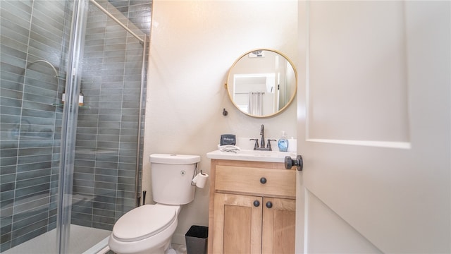 bathroom featuring a shower with shower door, toilet, and vanity