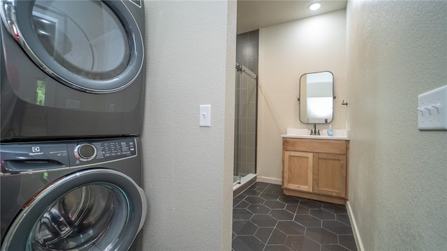 laundry room featuring sink, stacked washer / dryer, and dark tile patterned floors