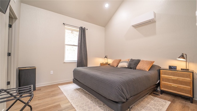 bedroom featuring lofted ceiling, light hardwood / wood-style flooring, and a wall mounted air conditioner