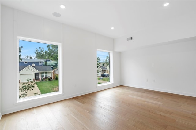 empty room featuring light wood-style flooring, visible vents, baseboards, and recessed lighting