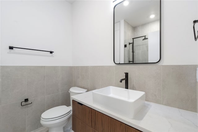 bathroom featuring toilet, a shower stall, tile walls, and vanity