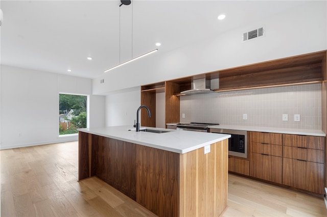 kitchen featuring a sink, visible vents, built in microwave, wall chimney exhaust hood, and modern cabinets