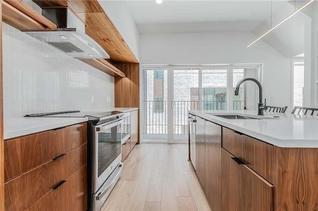 kitchen featuring brown cabinetry, appliances with stainless steel finishes, light countertops, open shelves, and a sink