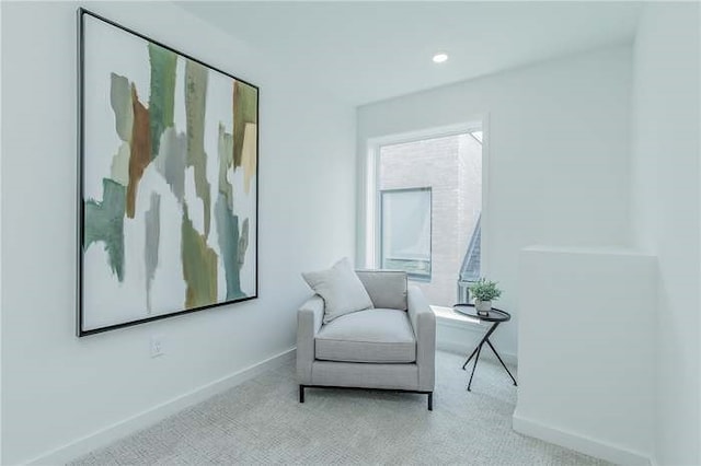 living area featuring baseboards and light colored carpet