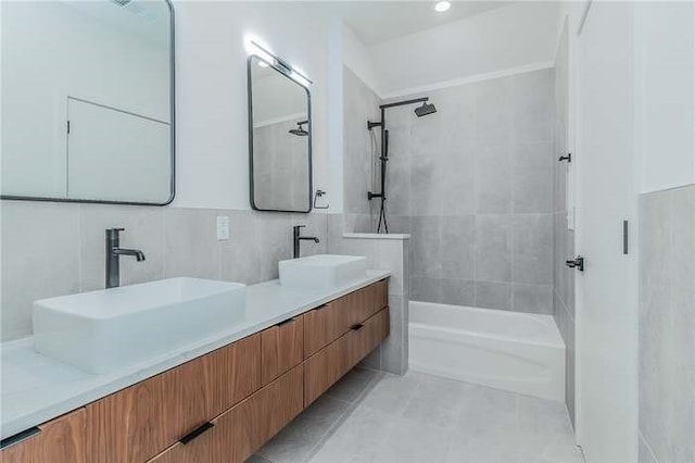 bathroom with a sink, tile walls, shower / bathtub combination, and double vanity