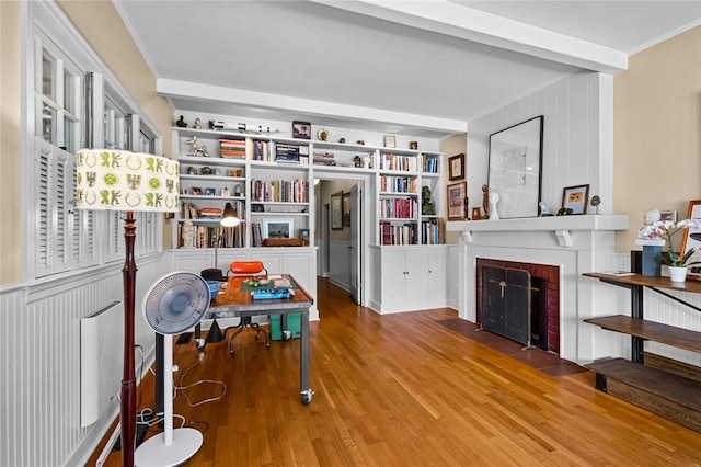 interior space with ornamental molding, wood-type flooring, and a brick fireplace