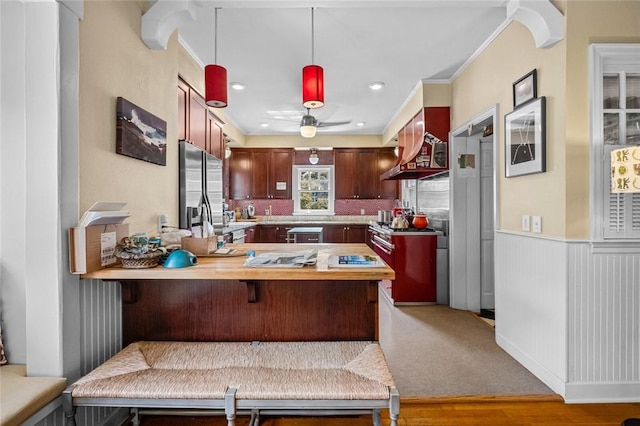 kitchen with crown molding, hanging light fixtures, a kitchen bar, stainless steel fridge with ice dispenser, and kitchen peninsula