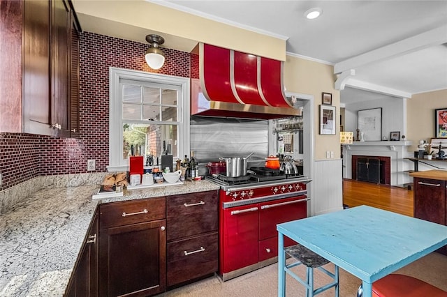 kitchen featuring light stone counters, ornamental molding, range with two ovens, and backsplash