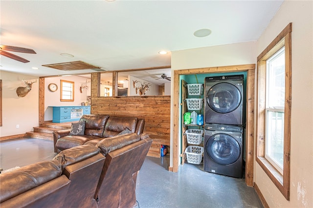 living room featuring concrete floors, stacked washer and dryer, and ceiling fan