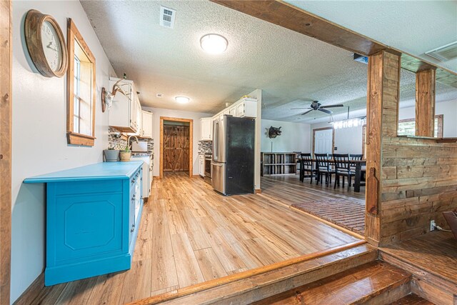 kitchen with ceiling fan, stainless steel refrigerator, white cabinets, and light hardwood / wood-style floors