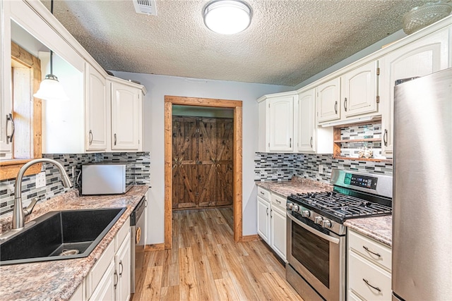 kitchen with white cabinetry, light hardwood / wood-style flooring, backsplash, stainless steel appliances, and sink