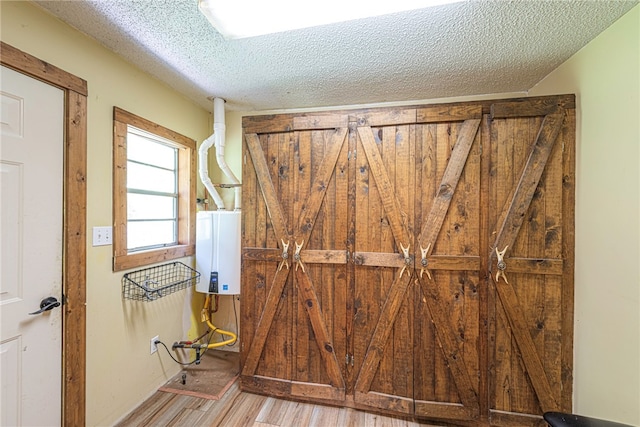 interior space featuring a textured ceiling, water heater, and wood-type flooring