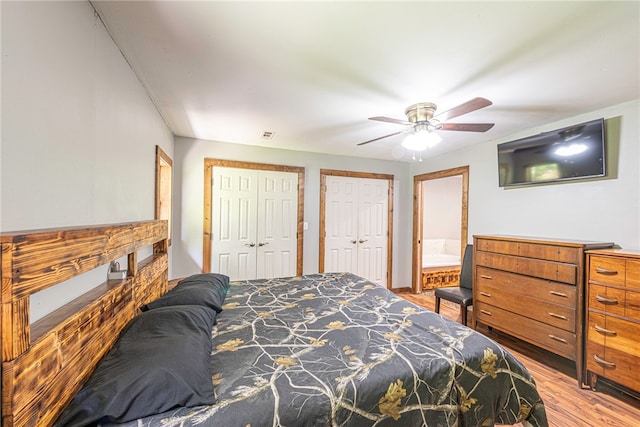 bedroom featuring two closets, ensuite bath, ceiling fan, and hardwood / wood-style floors