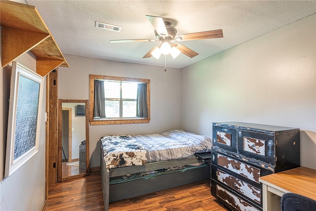 bedroom featuring a textured ceiling, ceiling fan, and dark hardwood / wood-style floors