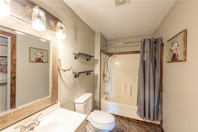 full bathroom with shower / bath combo with shower curtain, toilet, vanity, and a textured ceiling