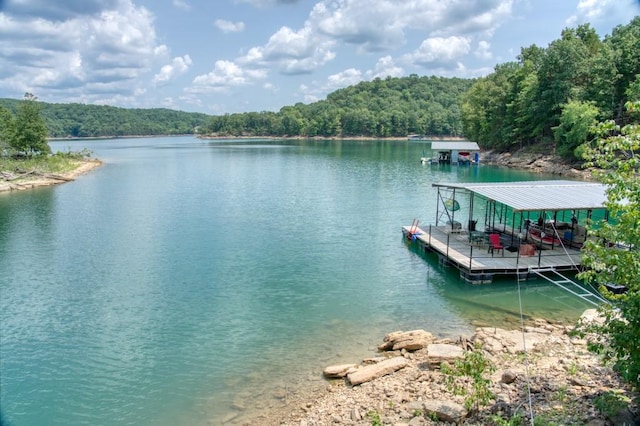 view of dock with a forest view and a water view