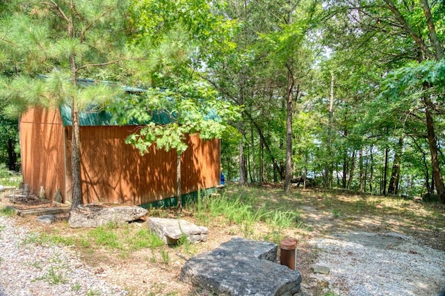 view of yard with an outbuilding and a view of trees