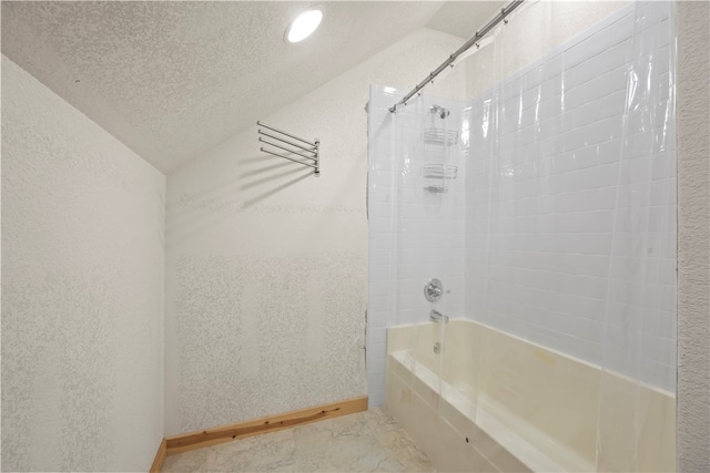 bathroom with lofted ceiling, a textured ceiling, and tiled shower / bath combo