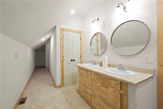 bathroom featuring a textured ceiling, vaulted ceiling, and vanity