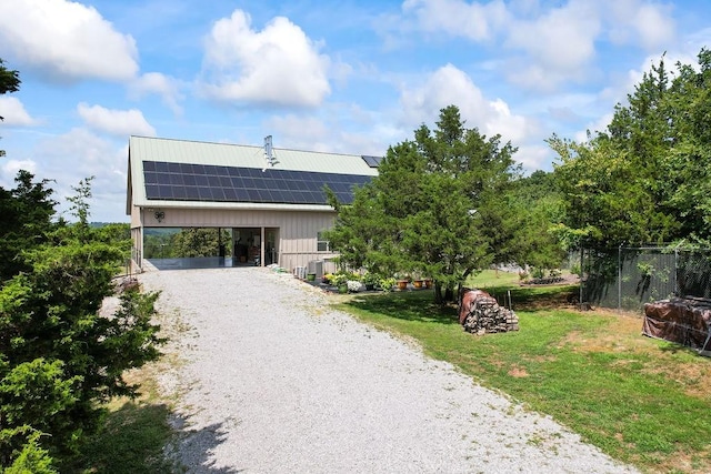 contemporary home with roof mounted solar panels, gravel driveway, fence, cooling unit, and a carport