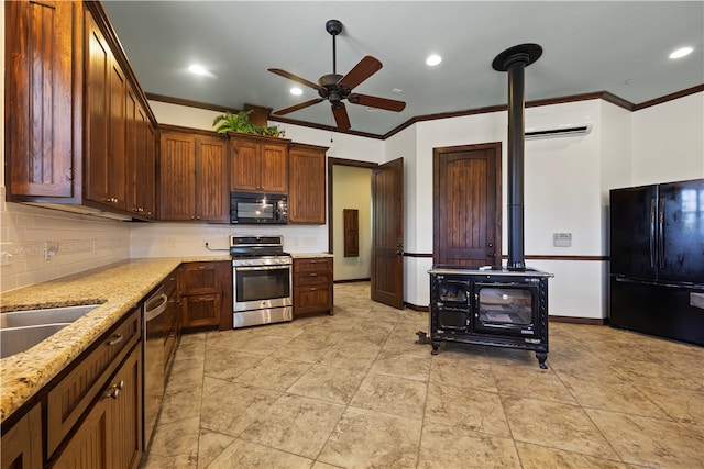 kitchen featuring ceiling fan, a wood stove, black appliances, light stone countertops, and crown molding