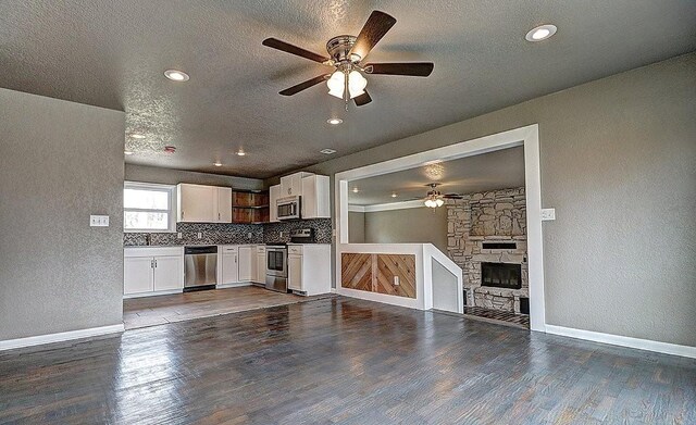 kitchen featuring appliances with stainless steel finishes, white cabinetry, dark hardwood / wood-style flooring, decorative backsplash, and a textured ceiling