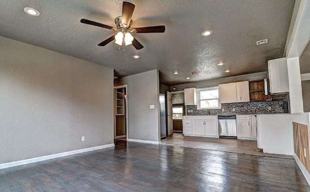 kitchen with dark wood-type flooring, white cabinetry, a textured ceiling, stainless steel appliances, and decorative backsplash