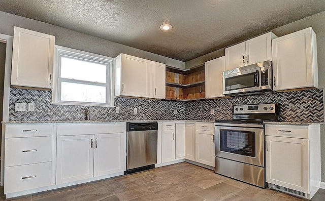 kitchen with appliances with stainless steel finishes, sink, white cabinets, backsplash, and a textured ceiling