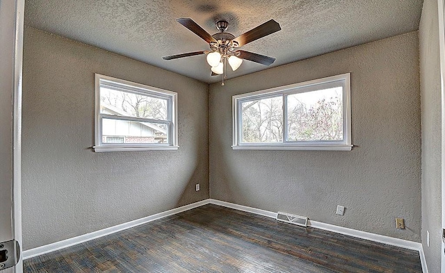 spare room with dark hardwood / wood-style flooring, ceiling fan, plenty of natural light, and a textured ceiling