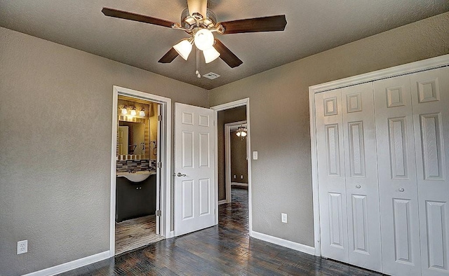 unfurnished bedroom featuring ceiling fan, ensuite bathroom, dark hardwood / wood-style floors, and a closet